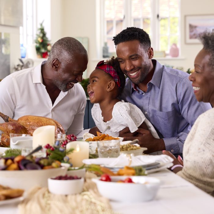 Multi-Generation Family Celebrating Christmas At Home With Grandfather Serving Turkey
