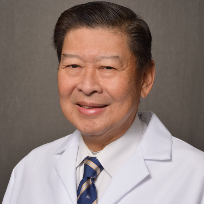 man with short black hair in lab coat and tie