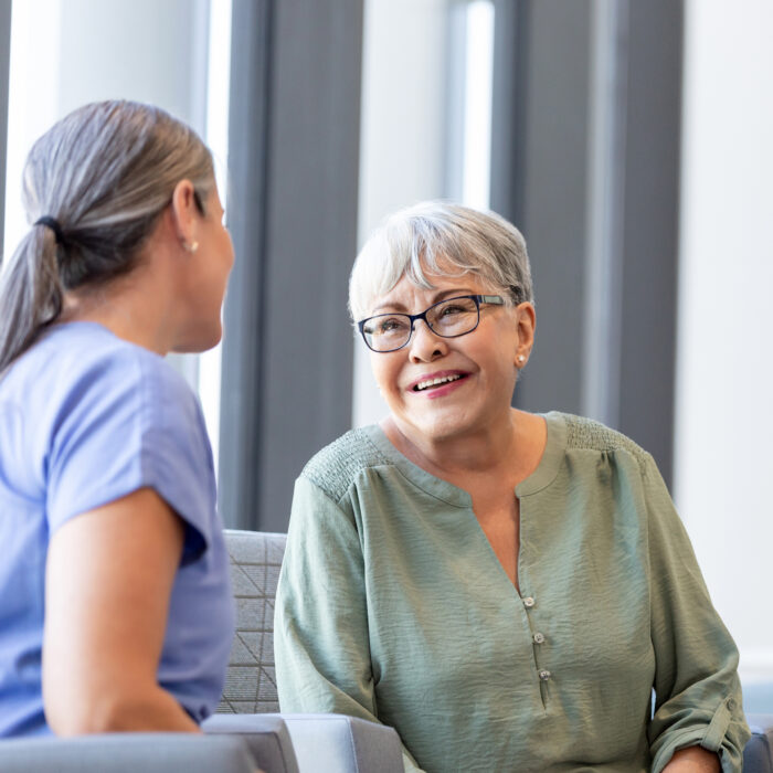 After hearing the results of her biopsy, the senior adult woman smiles while talking to her doctor.