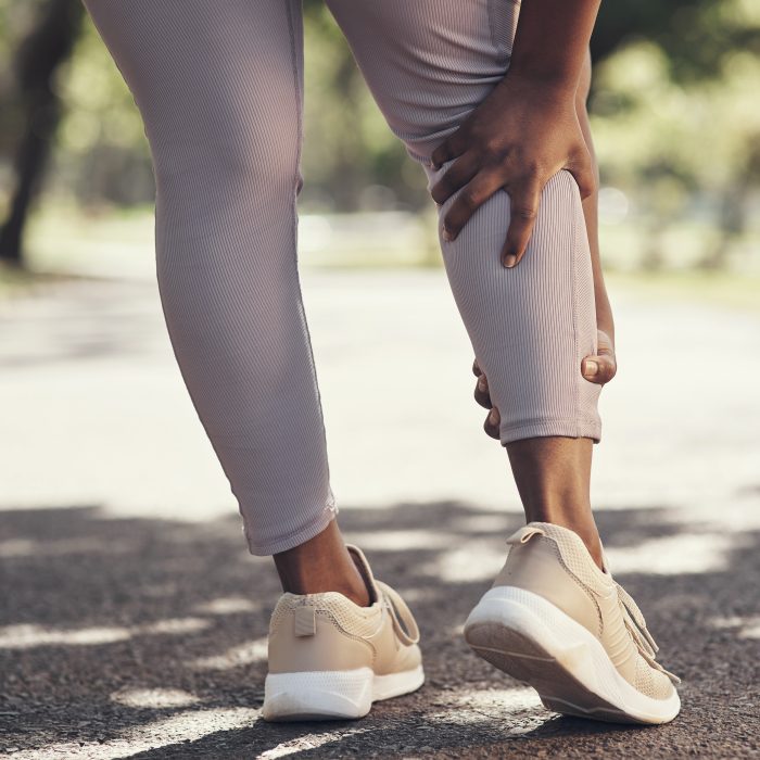 Shot of a woman massaging an injury in her leg