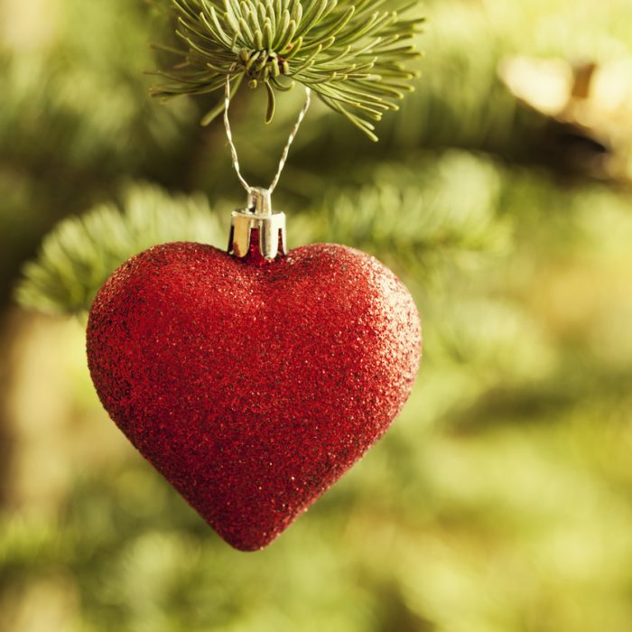 glittery christmas bauble in heart shape hanging in christmas tree
