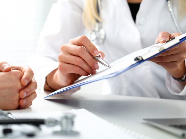 Female doctor hand hold silver pen filling patient history list