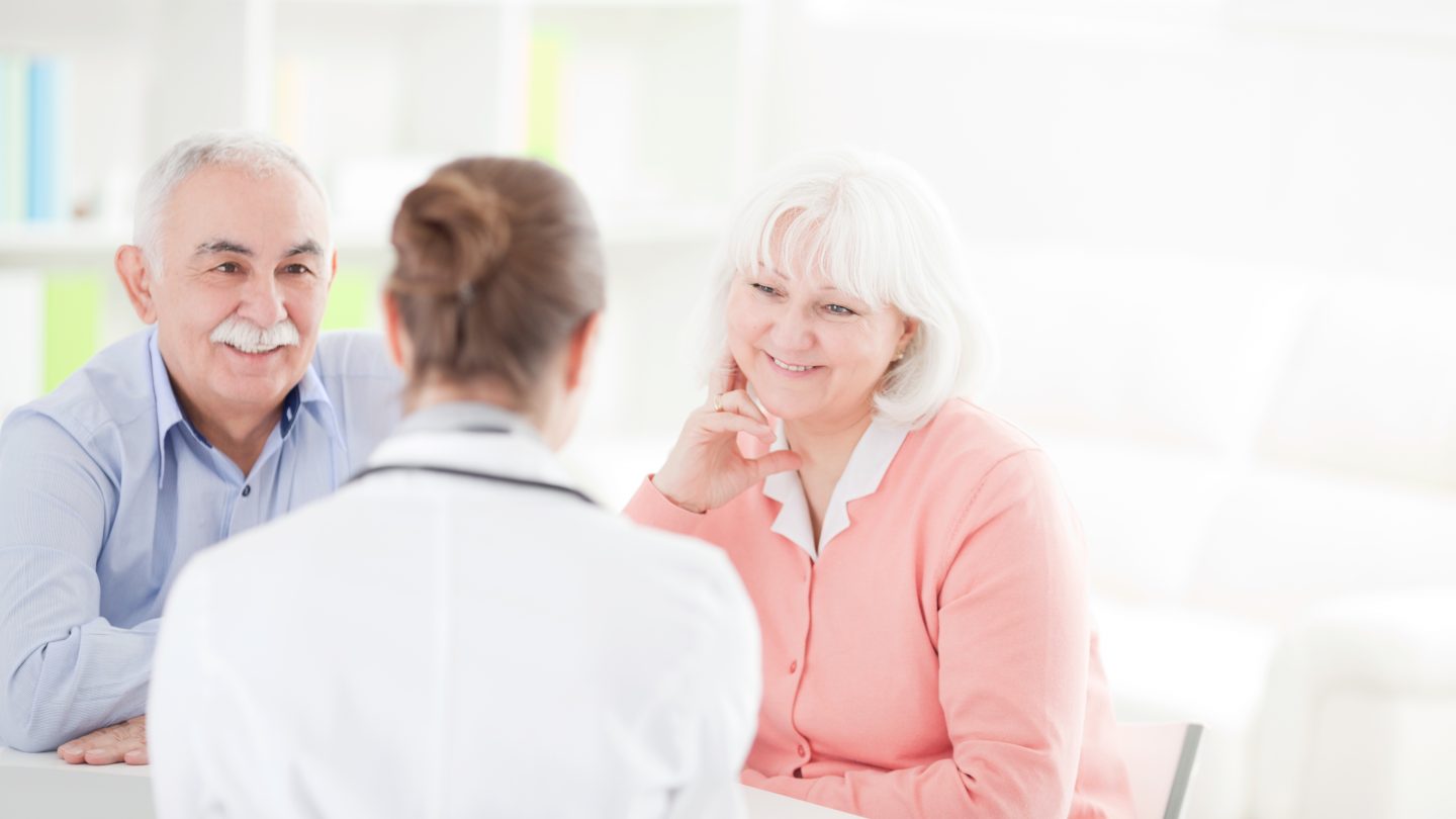 Senior woman with her husband at doctor's office measuring blood pressure.