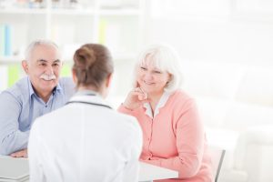 Senior woman with her husband at doctor's office measuring blood pressure.